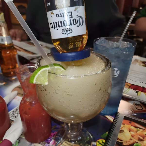 A large Cazadores Mexican Restaurant margarita with a Coronita beer bottle inverted into it.