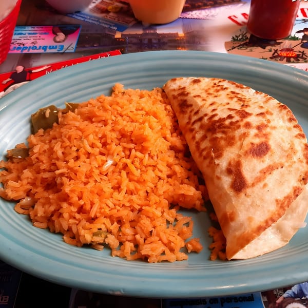 A Cazadores Mexican Restaurant meal with a quesadilla and orange rice on a blue plate.